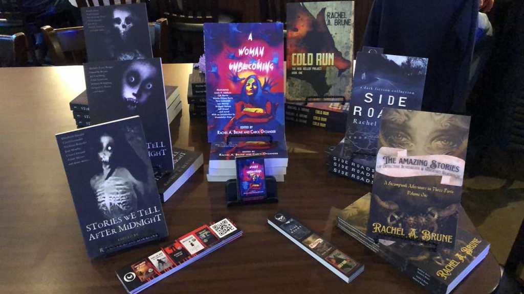 Seven books arrayed on a table of various titles with business cards arranged in front.